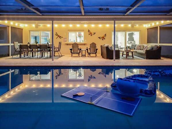 A pool area with a table and paddle, surrounded by seating and decorative butterfly wall art.