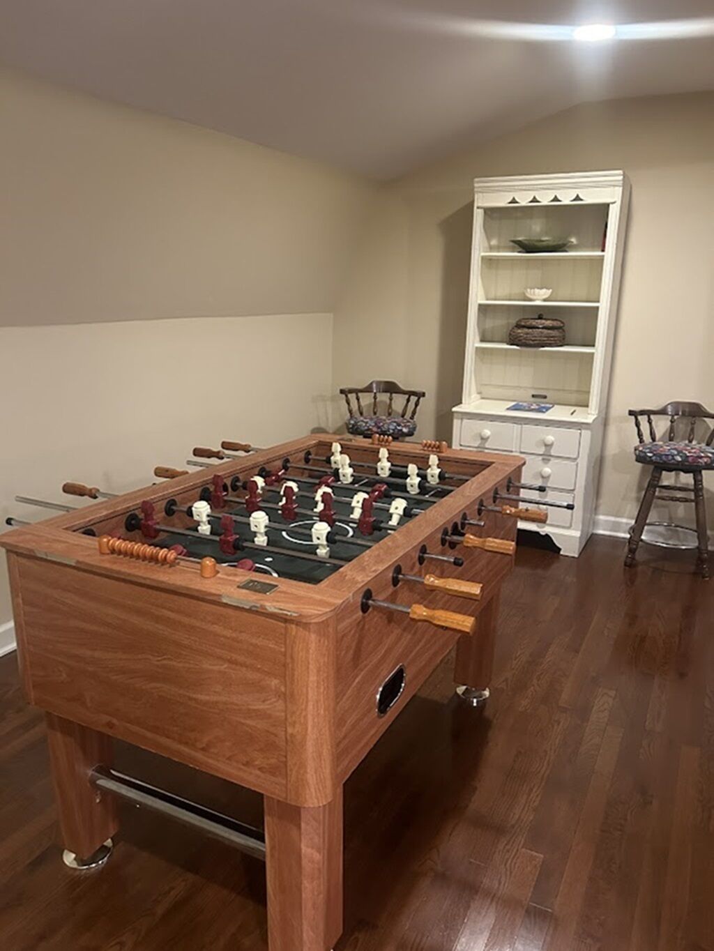 Ein Holztischkicker in einem Raum mit einem weißen Schrank und zwei Stühlen.