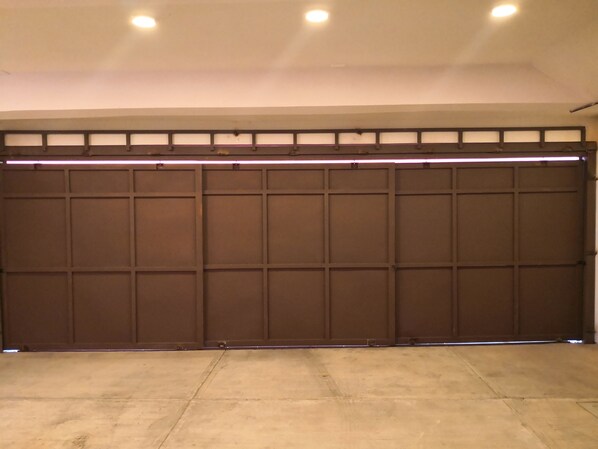 Un garage avec une porte coulissante marron, un sol en béton et un plafond doté d’un éclairage encastré.