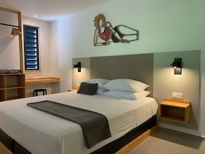 A modern bedroom with a large bed, bedside tables, a wall-mounted artwork, and a built-in shelf.