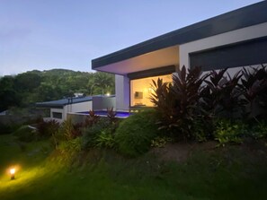 Et moderne hus med swimmingpool, omgivet af frodig vegetation.