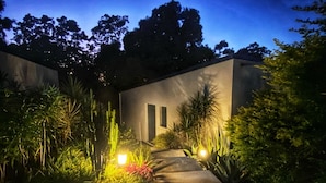 A modern building with a concrete exterior, surrounded by lush greenery and illuminated by warm lighting. - Villa Lune de Miel "champagne" Deshaies (Deshaies)