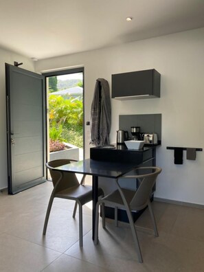 Une cuisine moderne avec une table et des chaises, un four encastré et une vue sur la verdure à l’extérieur.