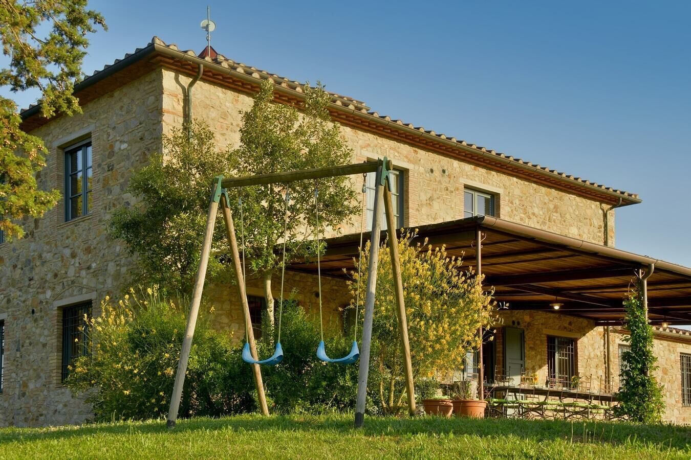 A stone building with a covered patio and a swing set.