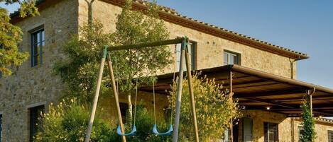 A stone building with a covered patio and a swing set.