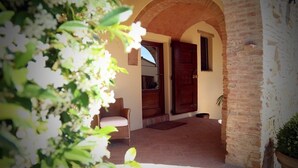An outdoor area with a wicker chair, a wooden door, and a brick wall. - Villa Elara - Tuscan Countryside Villa withPool (Montaione)