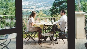 A couple dining at a table with a view of a town and hills.