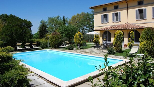 A pool with lounge chairs, a patio with tables and chairs, and a building with a tiled roof. - Villa Elettra - Private villa with pool in Umbria (Castiglione del Lago)