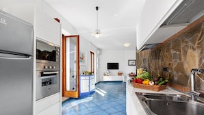 A modern kitchen with stainless steel appliances, a blue tiled floor, and a stone backsplash.