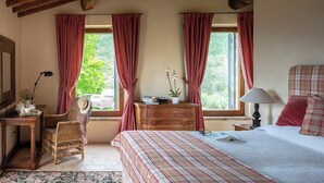 Une chambre à coucher comprenant un lit, une commode, une chaise, un bureau et une fenêtre avec des rideaux.