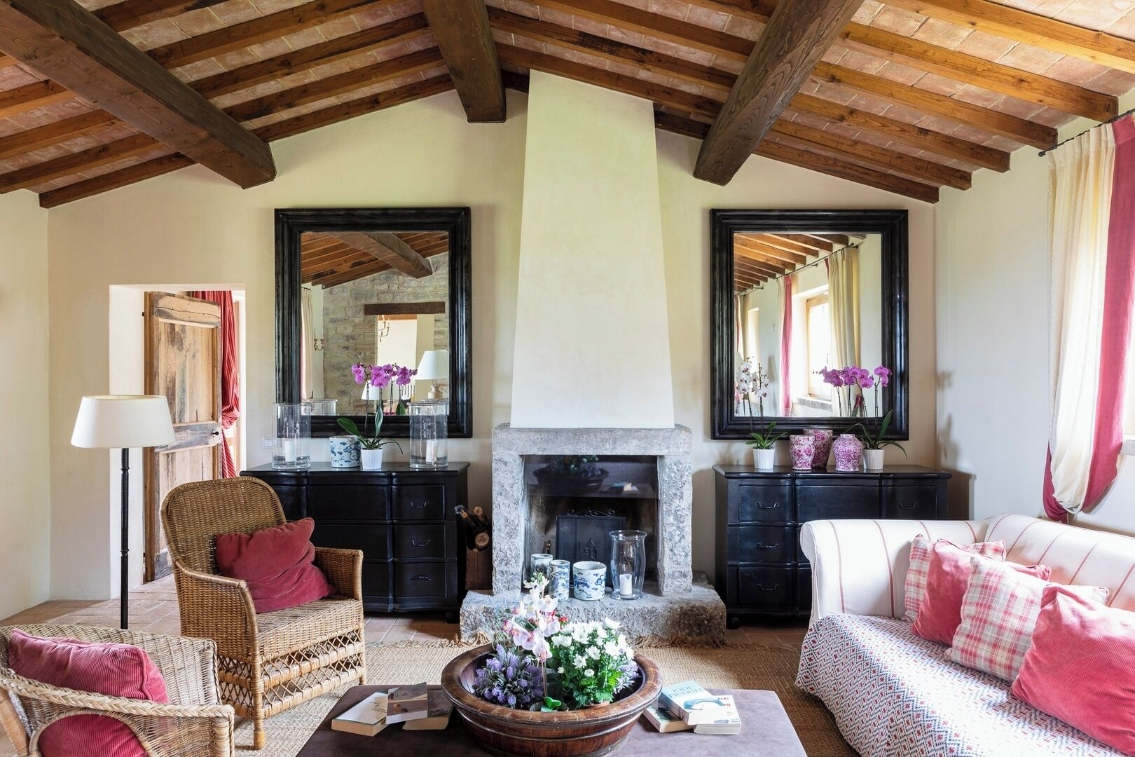 A cozy living room with a fireplace, wicker furniture, and a large mirror.