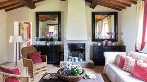 Un salon chaleureux avec une cheminée, des meubles en osier et un grand miroir.