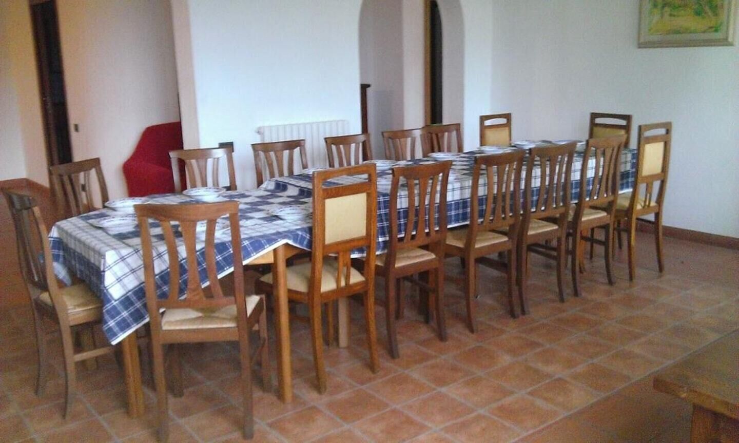 Un comedor con una mesa larga cubierta con mantel a cuadros, rodeada de sillas de madera.
