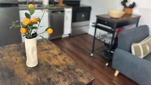 A living room with a wooden coffee table, a sofa, and a kitchen in the background. - 1BR 1B Hotel Like Ground Floor (Greenville)