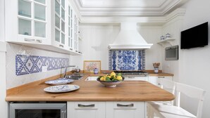 Une cuisine moderne avec des meubles blancs, un plan de travail en bois et des carreaux aux motifs bleus et blancs.