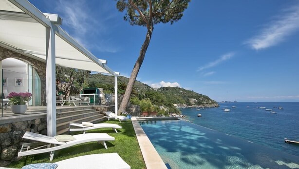 Un espace aménagé au bord de la piscine, avec des chaises longues et une vue sur la mer.