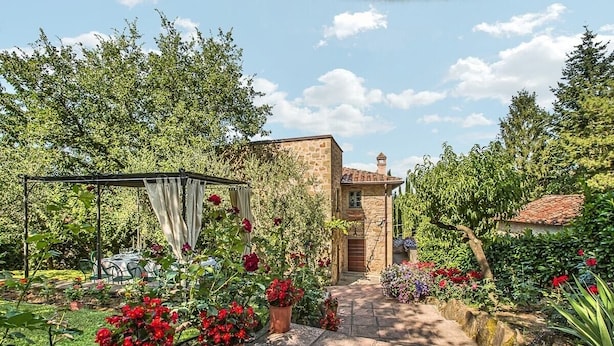 Ein Steinhaus mit einem Gartenweg, der zu einem überdachten Sitzbereich führt.