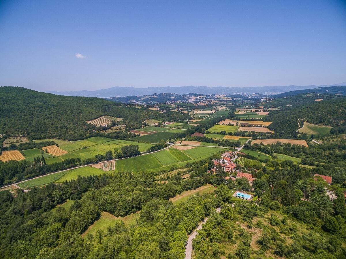 Une vue aérienne d’un paysage rural, avec des champs, des maisons et un ciel dégagé.