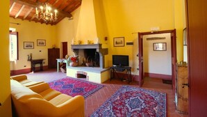 A living room with a fireplace, a television, and a sofa. - Villa Fausta - Tuscan Countryside Villa with Pool (Castiglion Fiorentino)