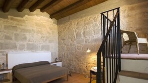 Un dormitorio con cama, mesita de noche, silla, lámpara y escalera.
