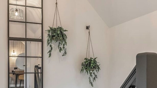Een trap met een metalen leuning en een spiegel met rasterpatroon aan de muur.