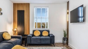 Een moderne woonkamer met een bank, een salontafel en een aan de muur bevestigde televisie.