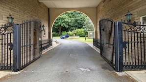 A covered driveway leading to a building with brick walls and black metal gates. - Stunning & Modern 2BD Flat - Manchester! (Salford)