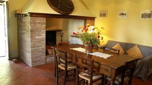 Uma sala de jantar com lareira de tijolos, mesa e cadeiras de madeira.