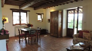 A spacious living area with a wooden dining table, chairs, a sofa, and a large cabinet.