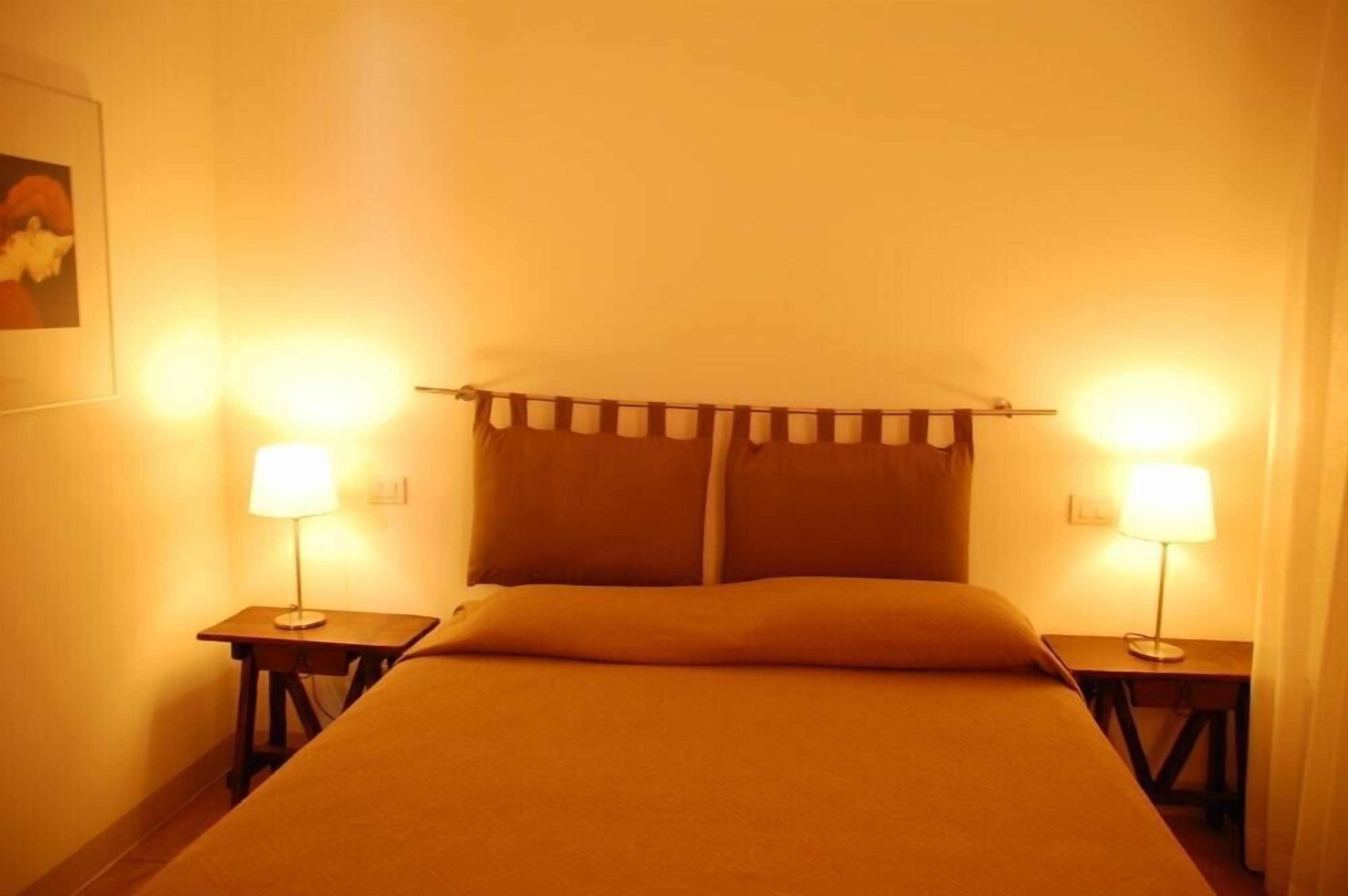 Une chambre d’hôtel avec un lit, deux tables de chevet et deux lampes.