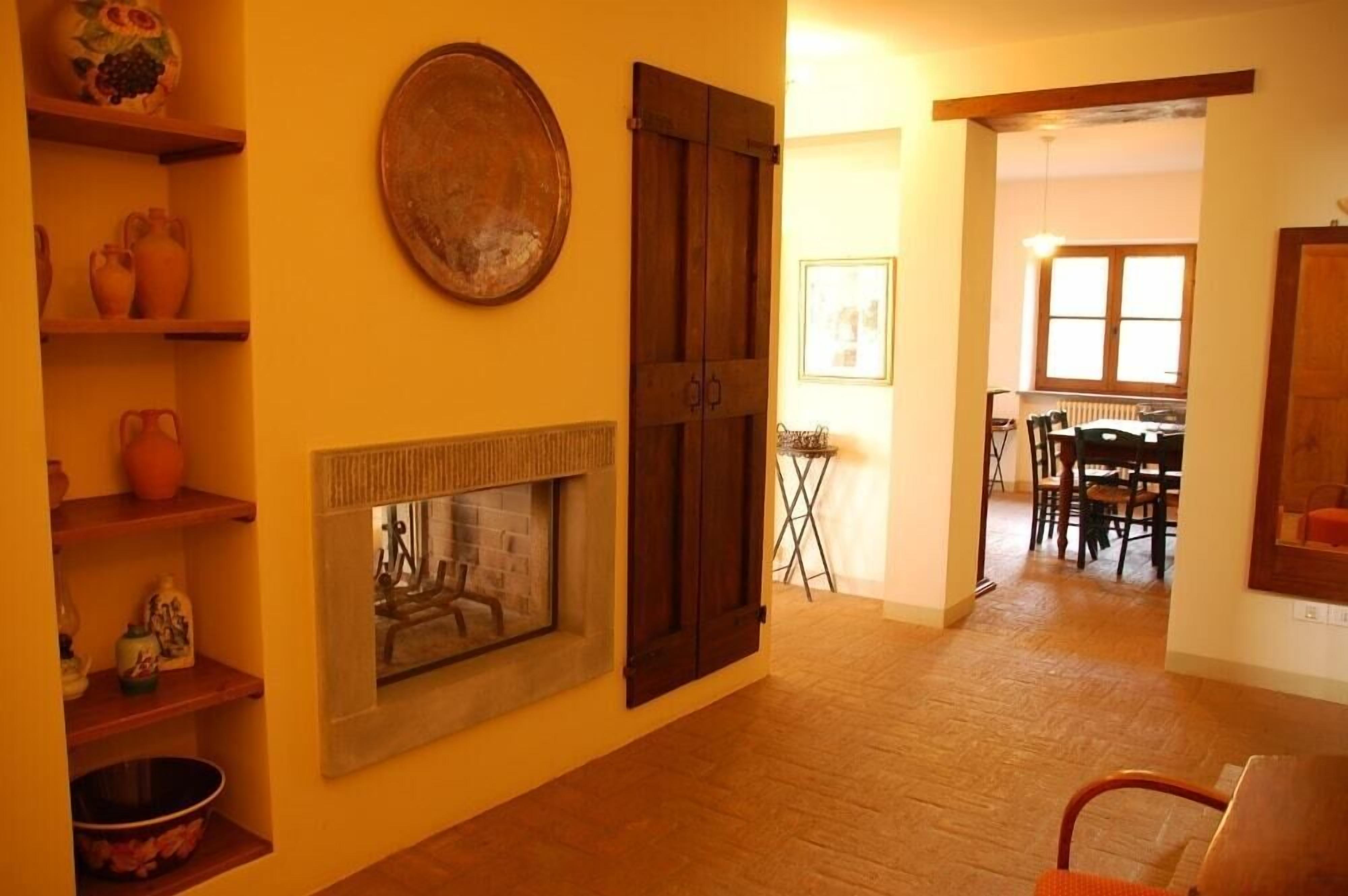 A room with a fireplace, wooden shelves, and a dining area with chairs and a table.