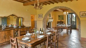A dining area with a wooden table set for a meal, a bar area with a mirror and fruit bowl, and a fireplace. - Villa Bibbona - Private villa with heated pool (Montecatini Val di Cecina)