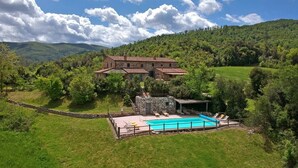 A villa with a swimming pool, surrounded by lush greenery and hills. - Villa Bibbona - Private villa with heated pool (Montecatini Val di Cecina)