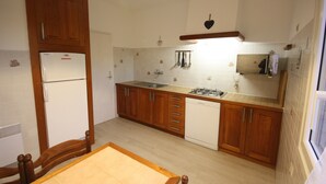 Une cuisine avec des meubles en bois, un réfrigérateur blanc, un lave-vaisselle et une cuisinière à gaz.