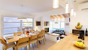 Une cuisine et une salle à manger modernes, dotées de meubles en bois, de grandes fenêtres et d’un four à micro-ondes encastré.