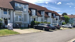 Una calle residencial con casas, coches estacionados y una bicicleta cubierta.