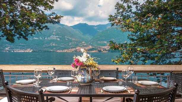 Mesa lista para comer con vista a un lago y montañas.