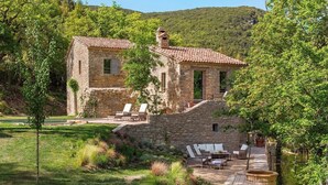 A stone building with a tiled roof, surrounded by a garden with outdoor seating and a pool. - Villa Anselma - Private Villa with Pool (Umbertide)