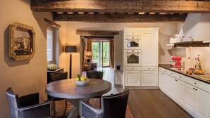 A rustic kitchen with wooden beams, white cabinets, and a dining area with a round table and chairs. - Villa Anselma - Private Villa with Pool (Umbertide)