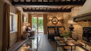 A cozy living room with a stone wall, a fireplace, and a view of the outdoors. - Villa Anselma - Private Villa with Pool (Umbertide)