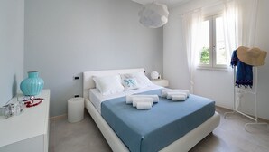 Une chambre à coucher moderne avec un lit, une table de chevet et une fenêtre avec des rideaux.