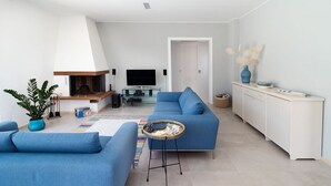 Un salon moderne avec un canapé bleu, une petite table ronde et un téléviseur en arrière-plan.