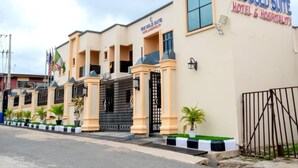 A hotel with a beige facade, a black gate, and a sign that reads "IRIS GOLD SUITE HOTEL & HOSPITALITY". - Iris-gold apartments (Ibadan)