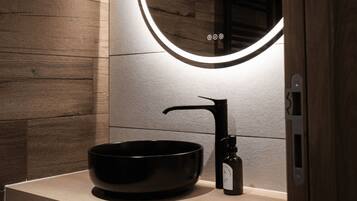Une salle de bain moderne avec un mur en bois, un lavabo noir et un miroir avec éclairage intégré.