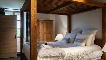 Ein Schlafzimmer mit einem Himmelbett, einem Holzschrank und einem Fenster mit Vorhängen.