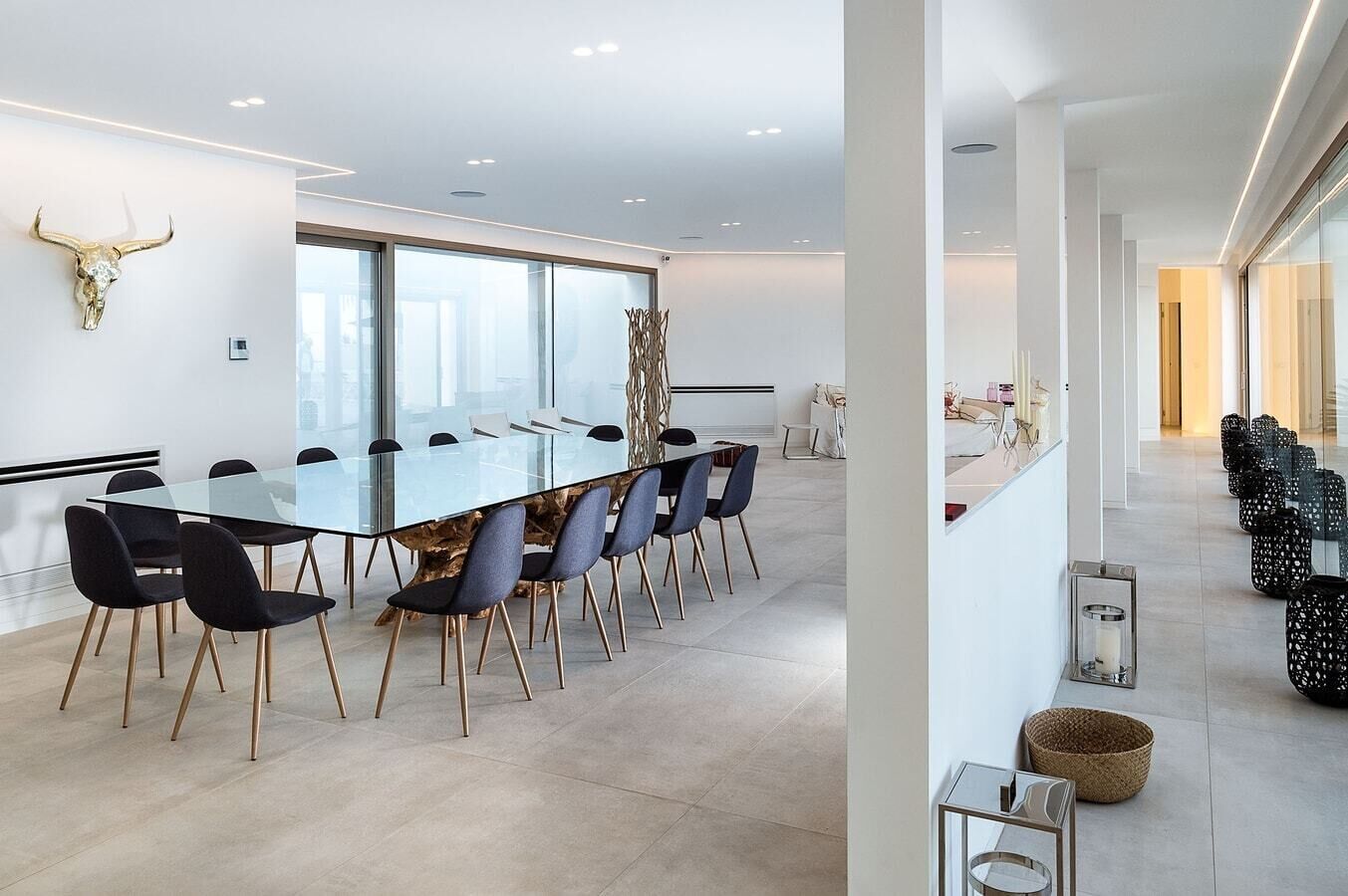 A modern conference room with a glass table, black chairs, and a bull skull decoration.