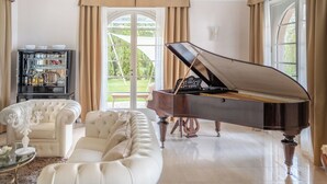 Un pianoforte a coda in un ampio soggiorno con un divano bianco e un tavolino da caffè in vetro.