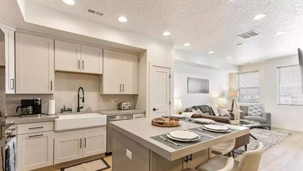 A modern kitchen with white cabinets, a central island with seating, and a dining area with a table set for four.