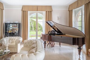 Un piano de cola en una sala de estar amplia con un sofá blanco y una mesa de centro de vidrio.