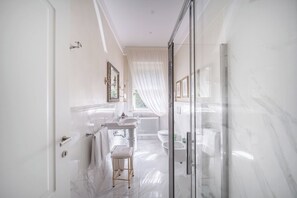 Un baño moderno con cabina de ducha de vidrio, un lavamanos blanco y un mueble de tocador con espejo.